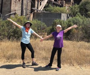 young girl and mother smiling and posing with arms wide in nature