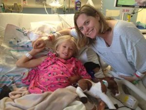 young girl and mother smiling together in hospital bed