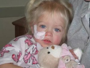 small child with breathing tube wearing pajamas holding stuffed plush bear