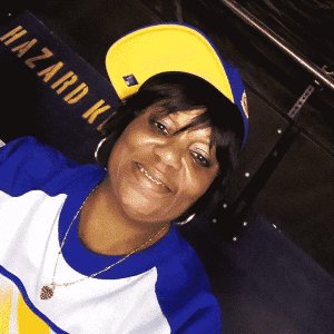 woman in baseball cap and jersey with gold necklace and hoop earings